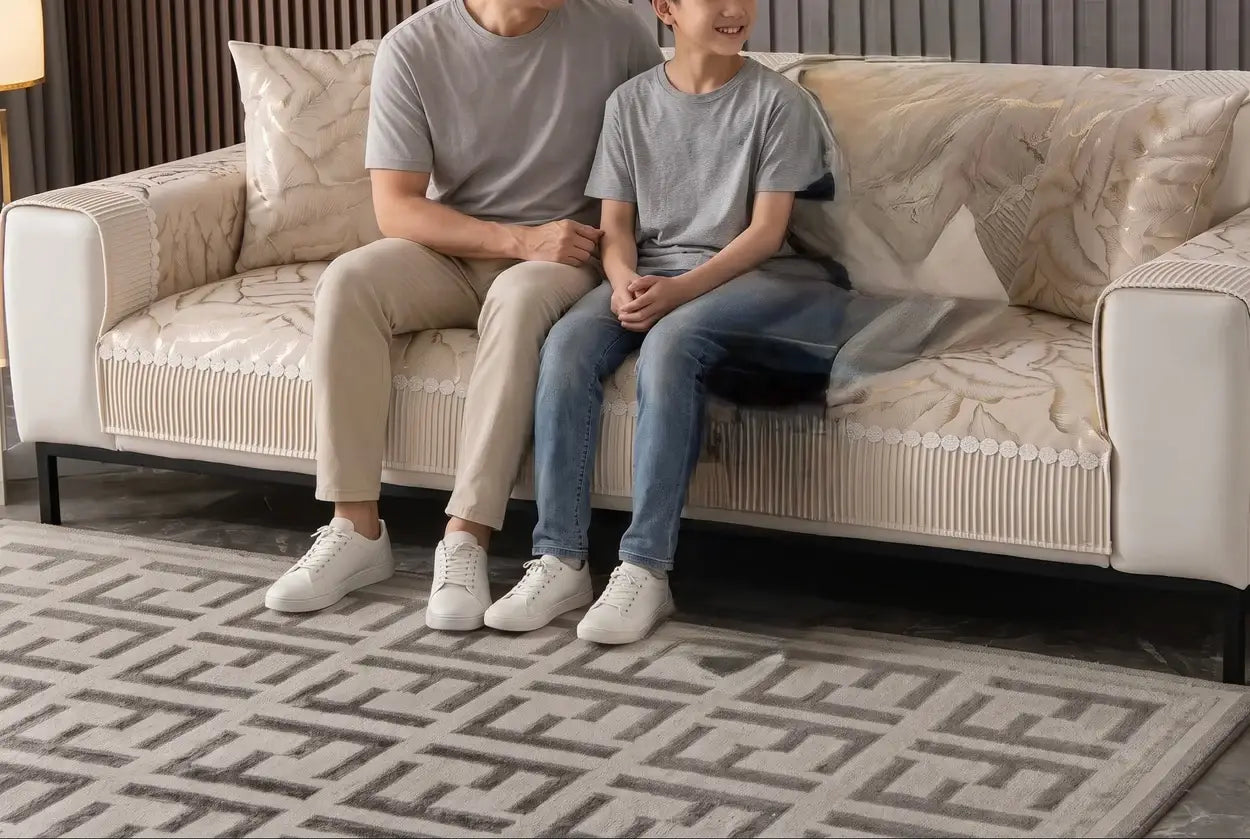 un papa et son fils assis sur le un canapé protéger par la housse de canapé feuille brodée