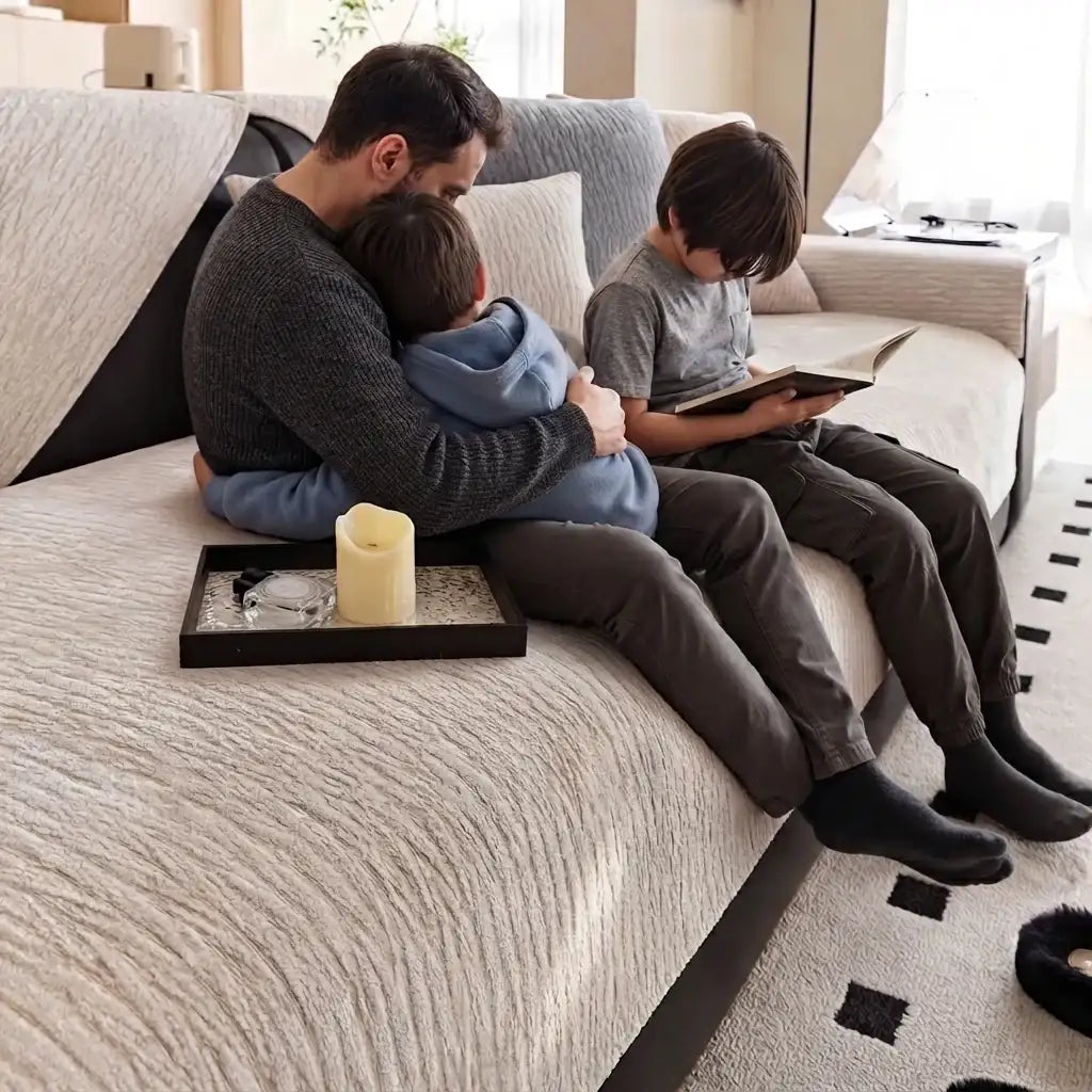 un papa et sesfils assis sur le un canapé protéger par la housse de canapé 2 places